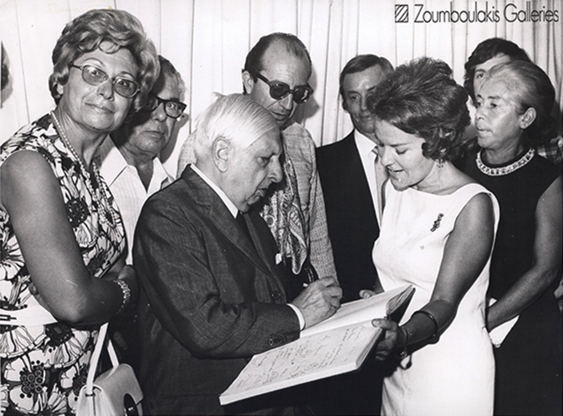 Έκθεση του De Chirico, δεκαετία του ’70. Ο καλλιτέχνης υπογράφει το βιβλίο σχολίων παρουσία της Πέγκυς.