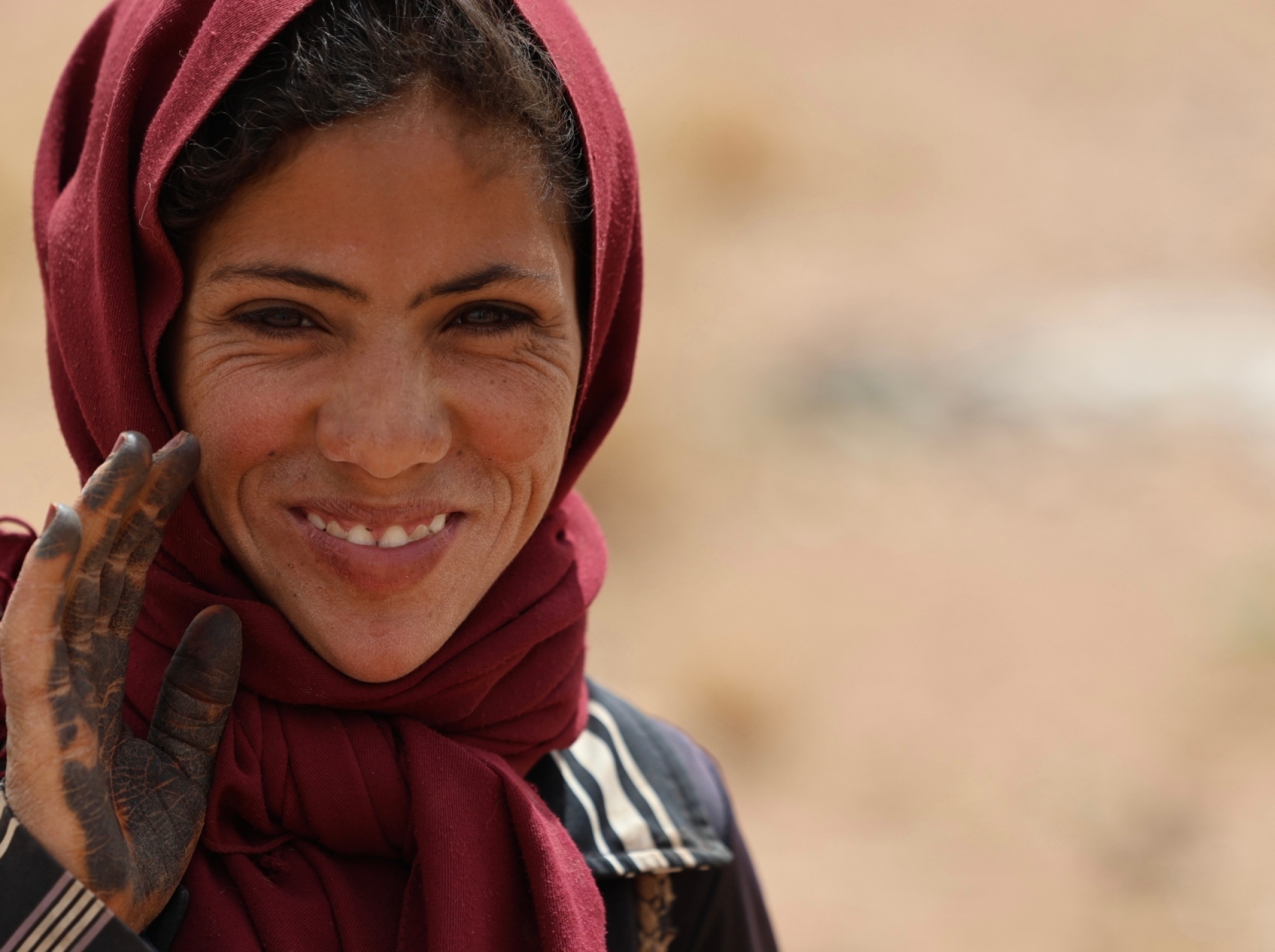 Η Φάτιμα χαμογελά στον φακό. Στην παλάμη της, τατουάζ από χένα