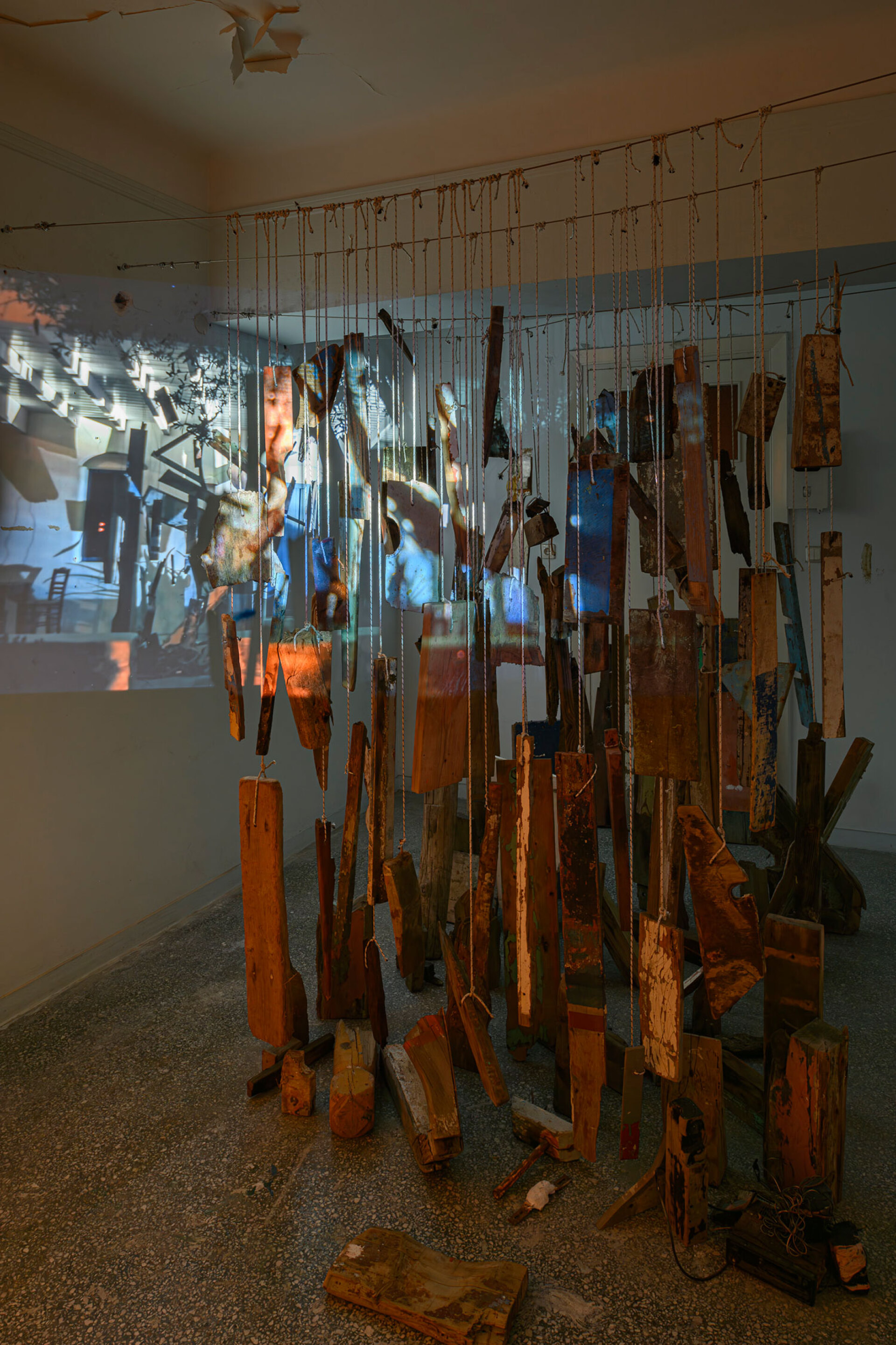 Δημήτρα Σκανδάλη, Ναυτικές Ιστορίες (2024) ξύλα από σπασμένα και βυθισμένα καΐκια, ευρεθέντα και δωρισμένα εργαλεία ψαράδων, σχοινιά, ανεμόσκαλα, πλαστικό, φύκια από τον Ειρηνικό Ωκεανό και από το Αιγαίο, καλάμια, ναυτικοί χάρτες, μονοκάναλη βιντεο-προβολή με ήχο [63’17’’], διαστάσεις μεταβλητές © Χρίστος Σιμάτος