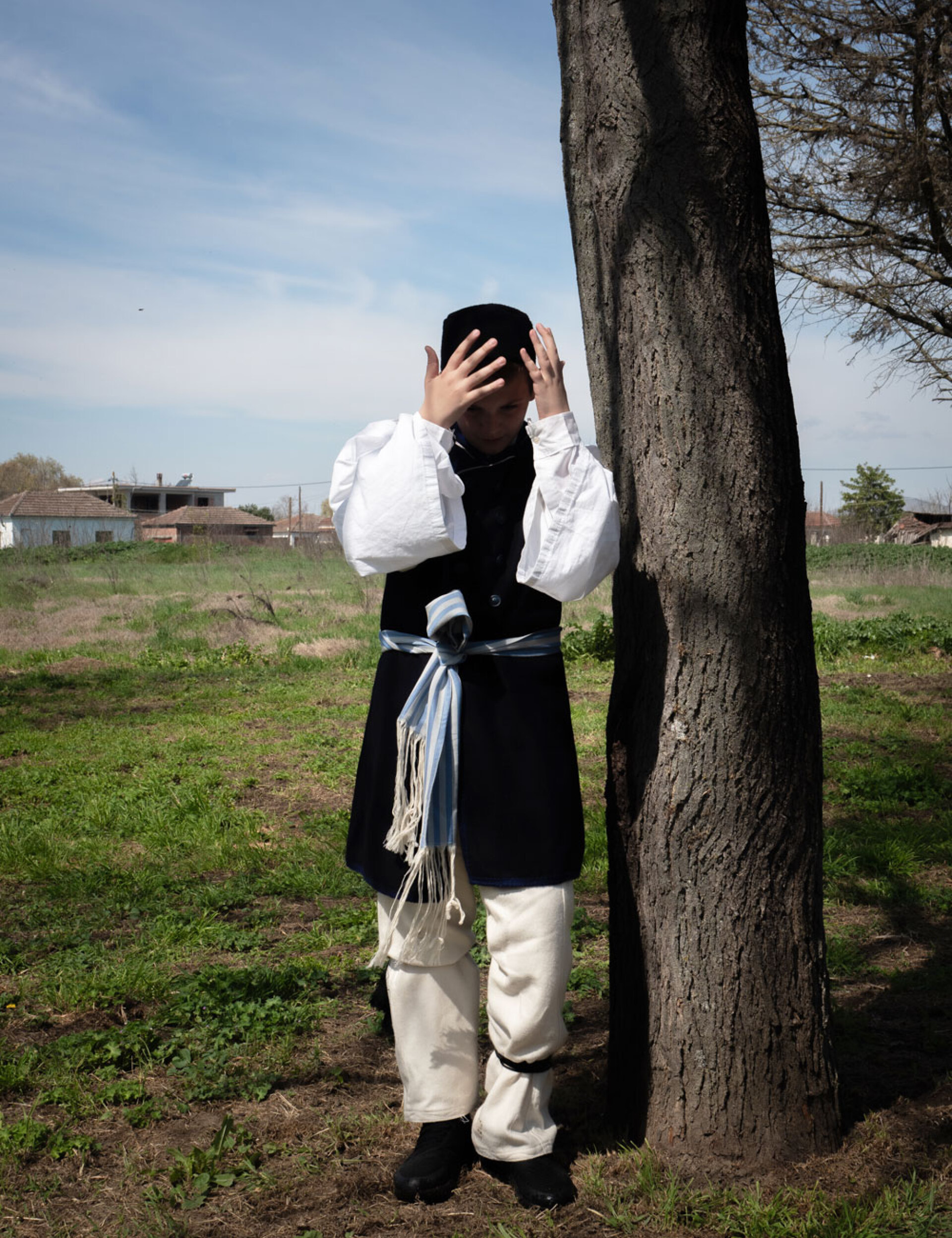 Νεαρό αγόρι με παραδοσιακή ενδυμασία παίζει κρυφτό με φίλους στο πανηγύρι του Παλαμά, μετά τη χορευτική του εμφάνιση