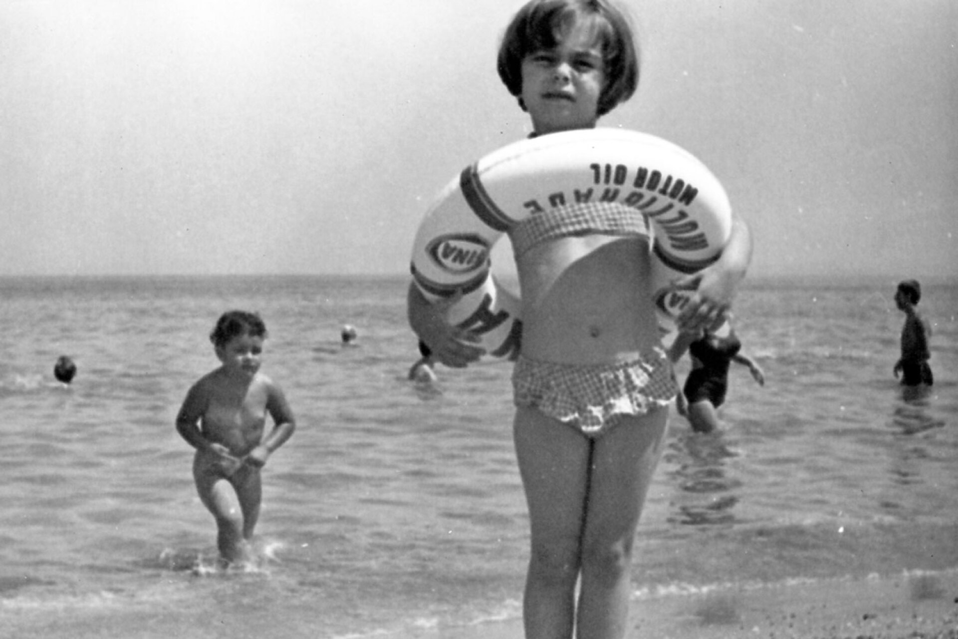 Μια μικρή κολυμβήτρια απολαμβάνει το νερό χρησιμοποιώντας μια σωσίβια ζώνη από την πετρελαϊκή εταιρεία FINA, ένα δημοφιλές διαφημιστικό δώρο της εποχής για τις οικογένειες με αυτοκίνητο, 1966
