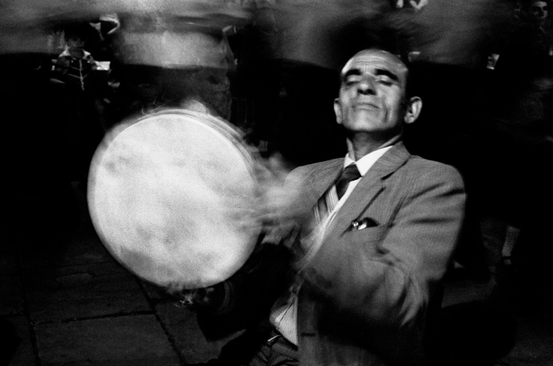 άντρας με κουστούμι που παίζει μουσικό όργανο σε πανηγύρι 