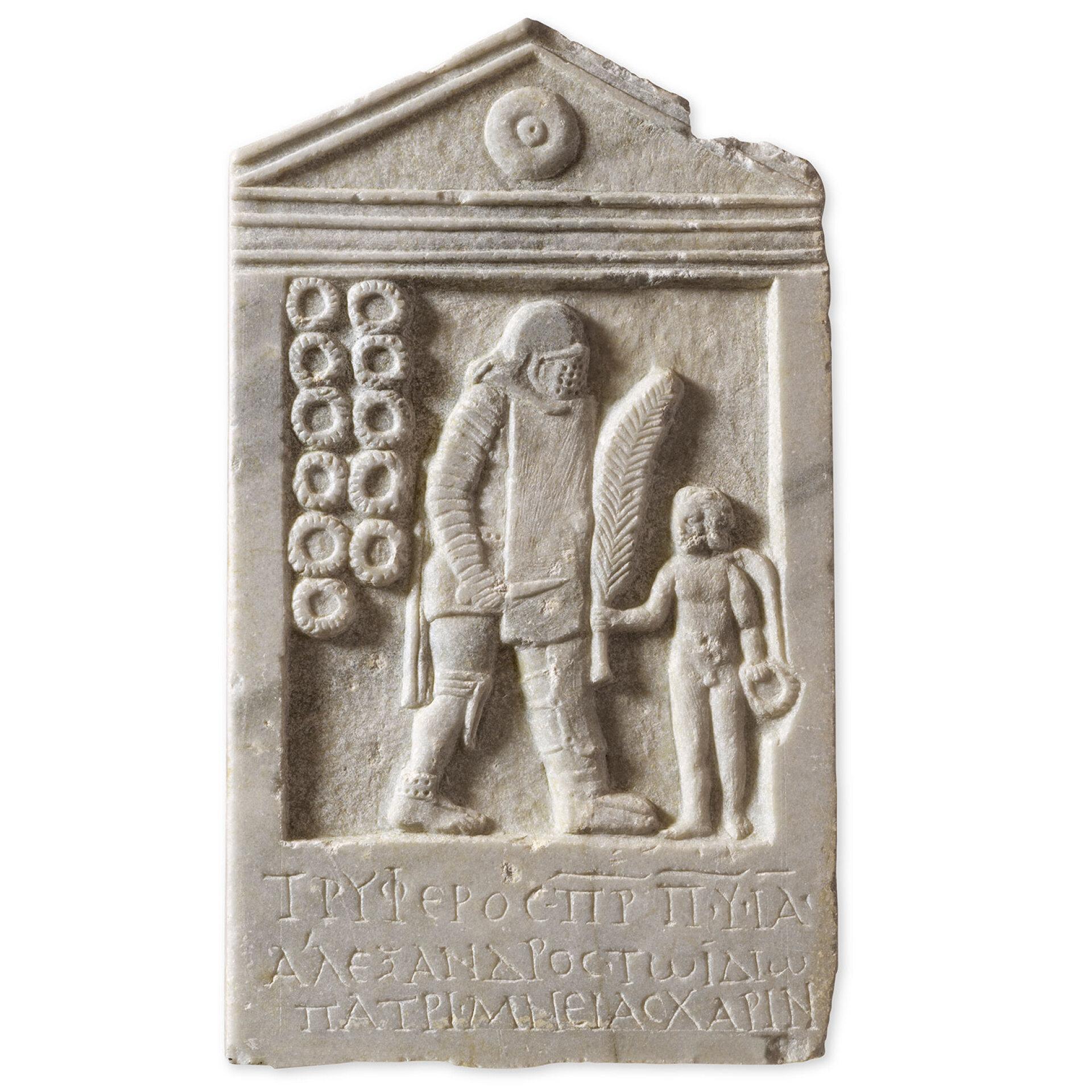 Μαρμάρινη επιτύμβια στήλη του μονομάχου Τρύφερου, την οποία προσέφερε στη μνήμη του ο γιος του, Αλέξανδρος. Ο μονομάχος βαριά οπλισμένος, στον τύπο του διώκτη, στρέφεται προς τα δεξιά. Αριστερά της παράστασης, έντεκα στεφάνια συμβολίζουν τις νίκες του στον στίβο. Πάτρα, Βόρειο νεκροταφείο, 2ος-3ος αι. μ.Χ. © Lamda Development