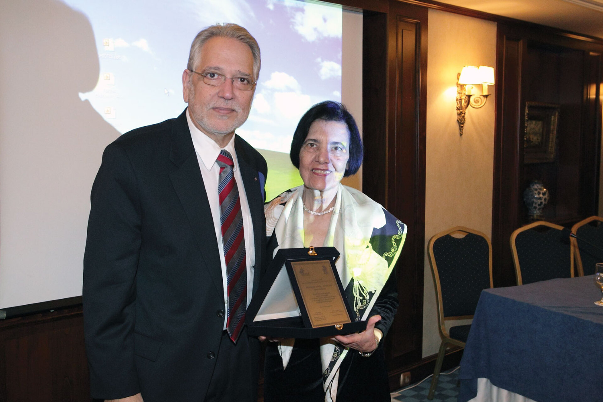 Ο Γιώργος Χρούσος της απονέμει τιμητική πλακέτα για την προσφορά της
