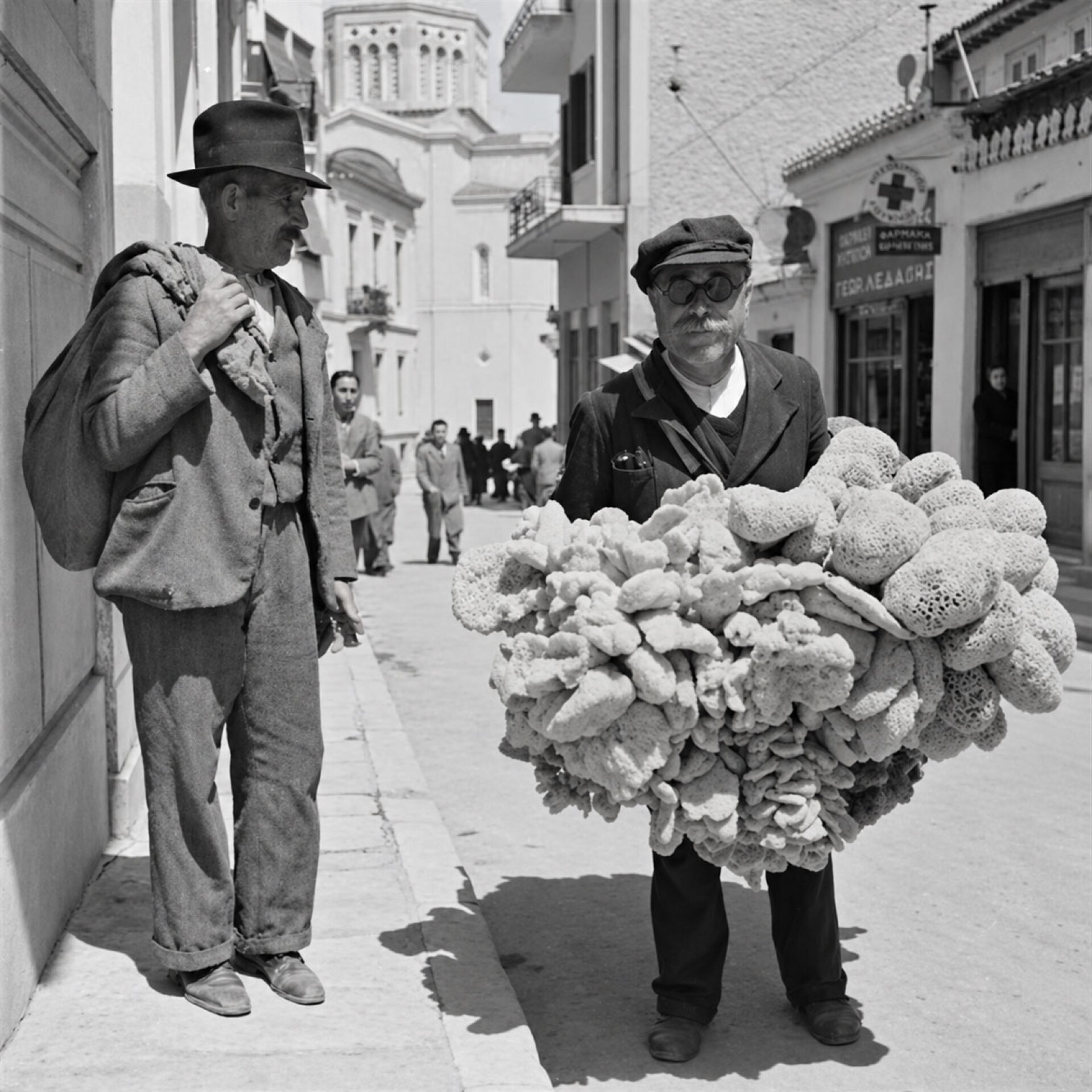 Πλανόδιος πωλητής σφουγγαριών σε γειτονιά της Αθήνας, με πραμάτεια κυρίως από τα νησιά του Αιγαίου | Φωτογραφία: Βούλα Θεοχάρη Παπαϊωάννου, 1945-1955 (ΦΑ_6_601)