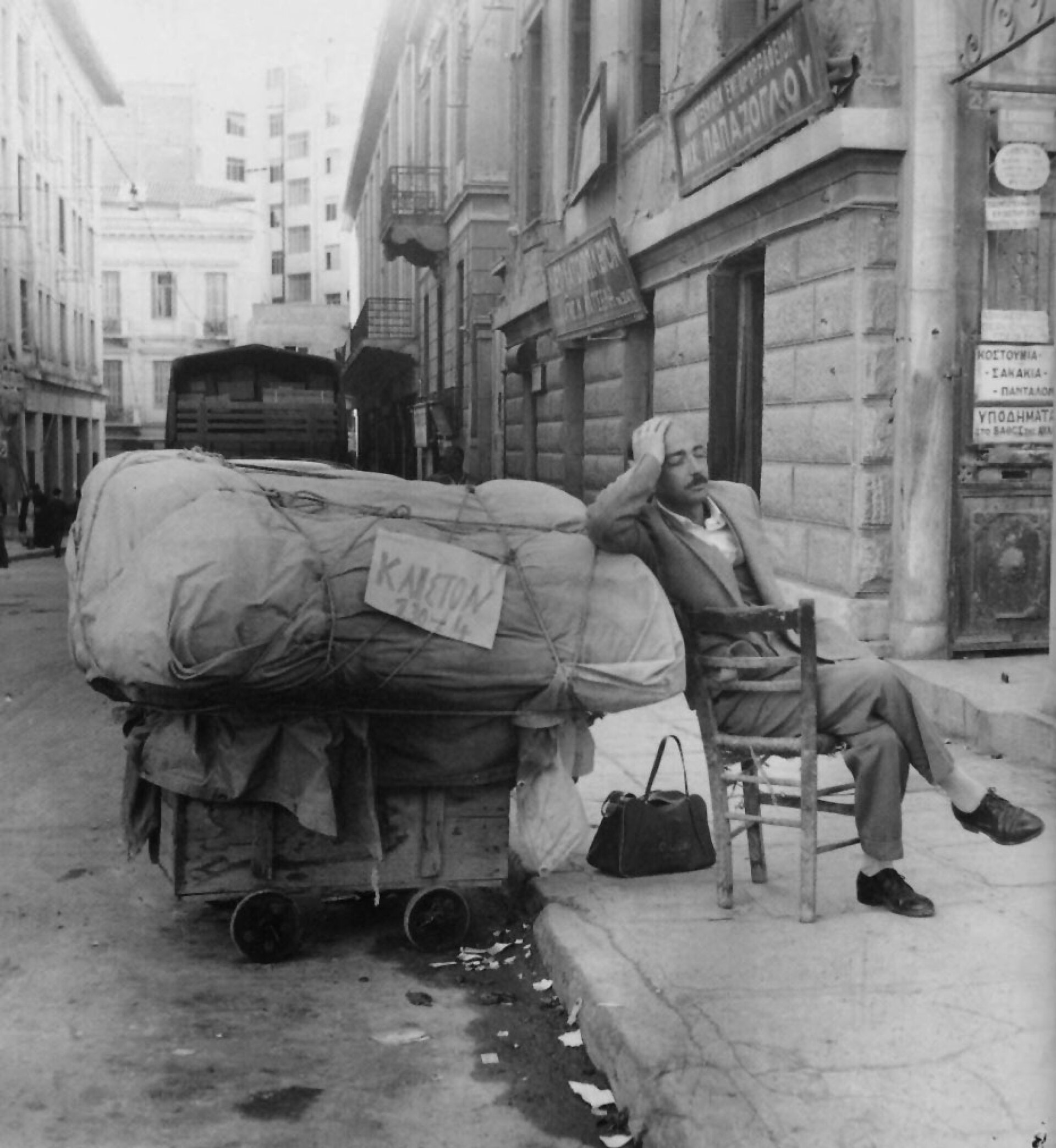 Το κατάστημα έχει κλείσει, όμως η πινακίδα με τον αριθμό αδείας παραμένει στη θέση της | Δίπλα στο καρότσι, ο μικροπωλητής βρήκε πρόχειρο αποκούμπι και ξεκουράζεται για λίγο