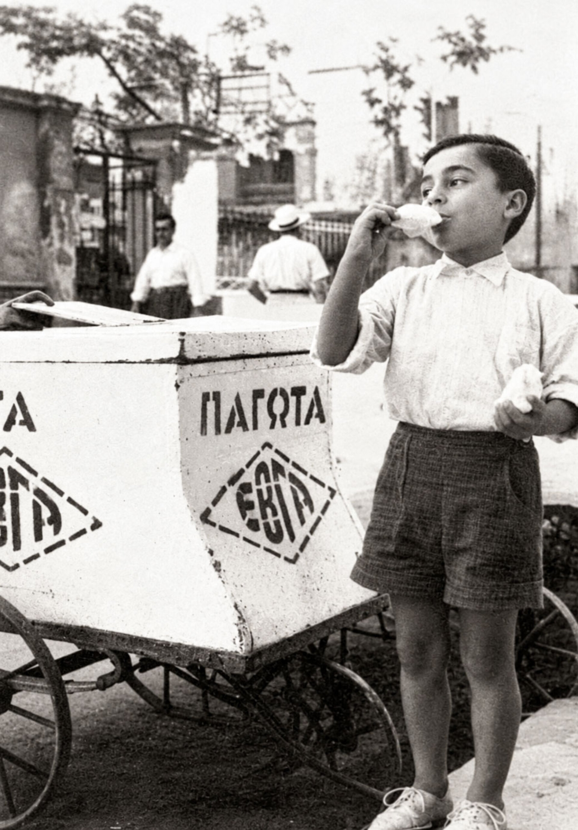 Παιδί απολαμβάνει παγωτό δίπλα σε πλανόδιο καρότσι παγωτατζή, σε μια χαρακτηριστική εικόνα της παλιάς Αθήνας