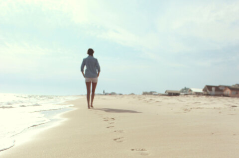 Γυναίκα περπατάει σε παραλία με άμμο