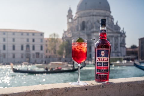 Μπουκάλι Select Aperitivo και ποτήρι Spritz Veneziano πάνω σε γέφυγα με φόντο τα κανάλια της Βενετίας