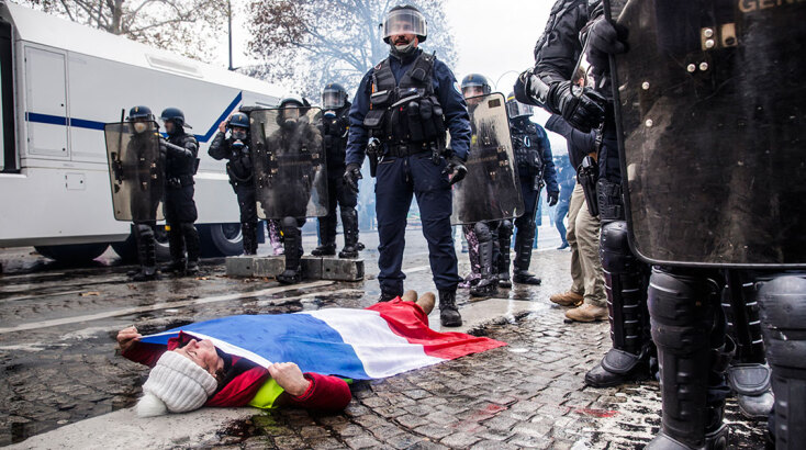 Διαδηλώτρια με τη γαλλική σημαία είναι πεσμένη μπροστά σε αστυνομικούς στο Παρίσι κατά τη διάρκεια διαμαρτυρίας που οργάνωσαν τα «Κίτρινα Γιλέκα»