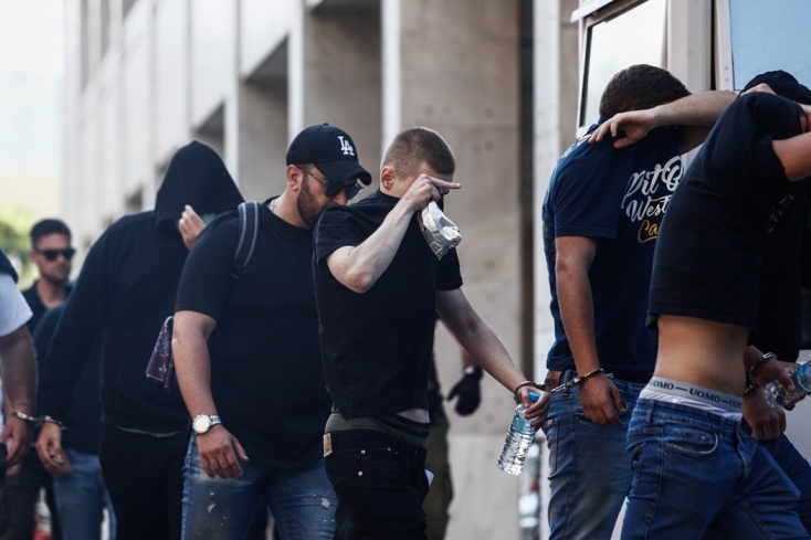 Συλληφθείς κάνει χειρονομία κρύβοντας το πρόσωπό του από τις κάμερες των δημοσιογράφων