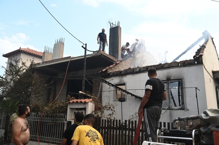Πολίτες προσπαθούν να σβήσουν τη φωτιά σε καμένο σπίτι