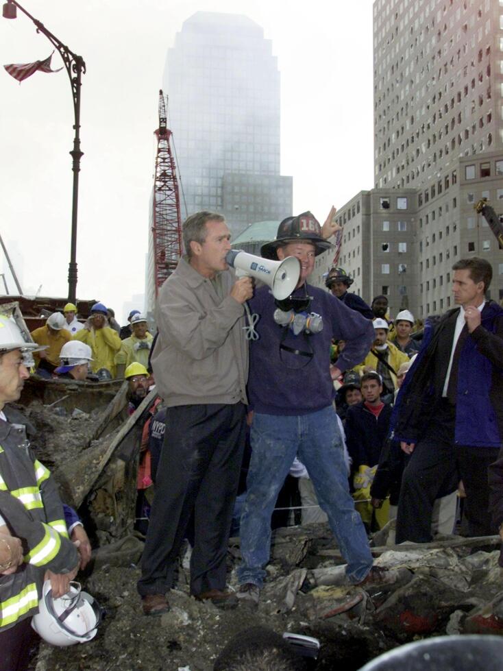 JFK45 - 20010914 - NEW YORK, NY, UNITED STATES : US President George W. Bush (L) speaks beside retired firefighter Bob Beckwith, 69, to volunteers and firemen at the site of the World Trade Center 14 September 2001 in New York. EPA PHOTO AFPI/PAUL RICHARDS/DRE/DEC-ms