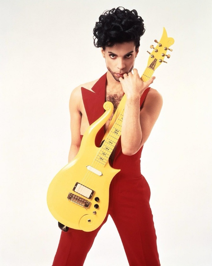 Ο Prince με κόκκινα ρούχα κρατώντας κίτρινη κιθάρα