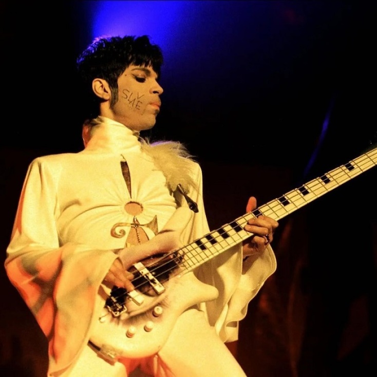 OPrince επί σκηνής παίζοντας κιθάρα και έχοντας τη λέξη slave γραμμένη στο μάγουλό του