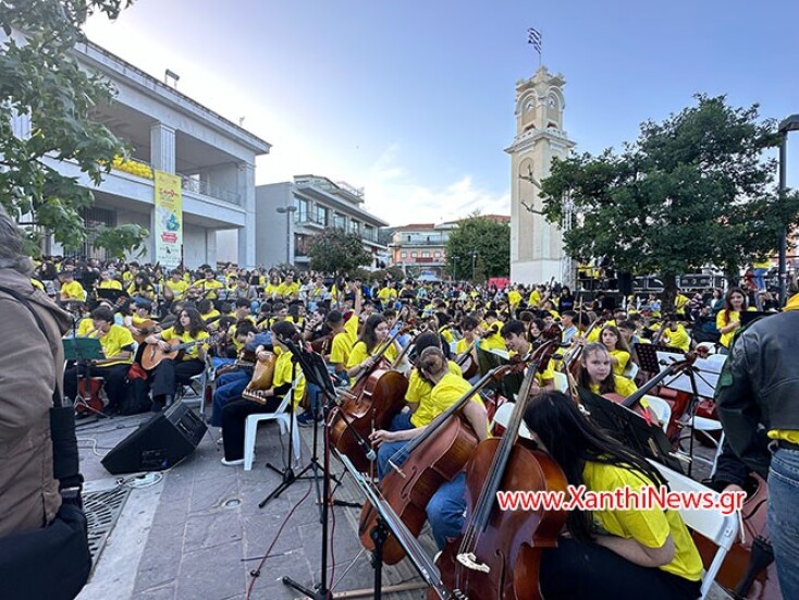 Δεκάδες μαθητές στα κίτρινα κρατάνε μουσικά όργανα καθιστοί