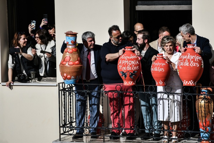 άτομα σε μπαλκόνι κρατώντας κόκκινες στάμνες