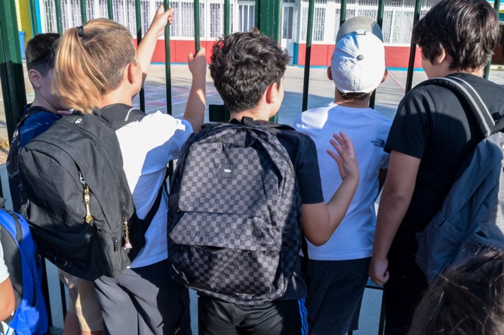 Μαθητές με τις τσάντες τους στην πλάτη αναμένουν να ανοίξει η πόρτα του σχολείου τους
