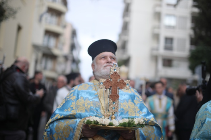 Ιερέας κρατά τον Σταυρό σε δρόμο της Αθήνας
