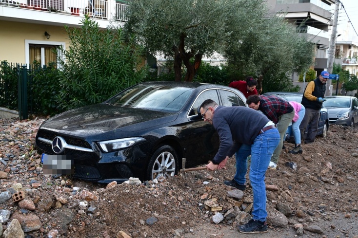 Πολίτες με φτυάρια και καρότσια απομακρύνουν πέτρες και άλλα αντικείμενα από τους δρόμους