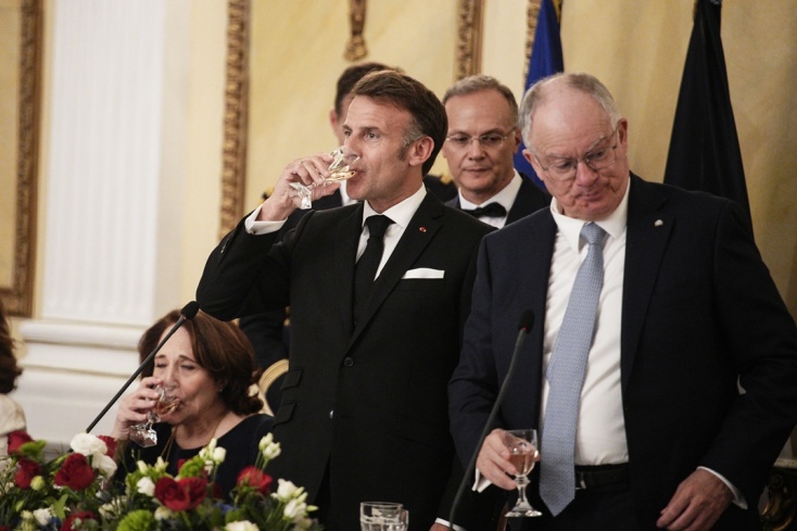 Εμανουέλ Μακρόν και Κωνσταντίνος Τασούλας πίνουν ποτό αφού έχουν τσουγκρίσει τα ποτήρια τους