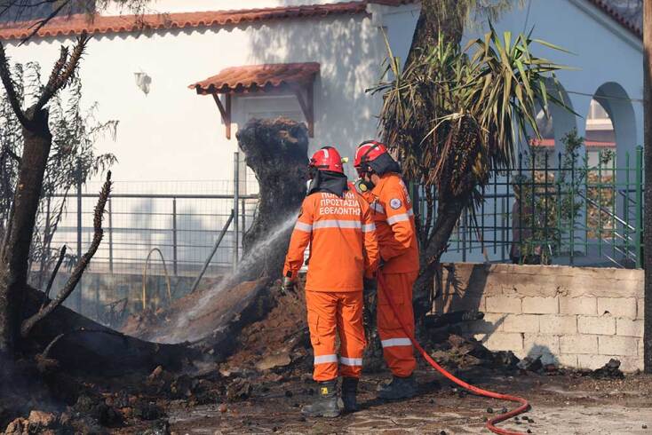 Πυροσβέστες επιχειρούν έξω από καμένο σπίτι στη Σαλαμίνα