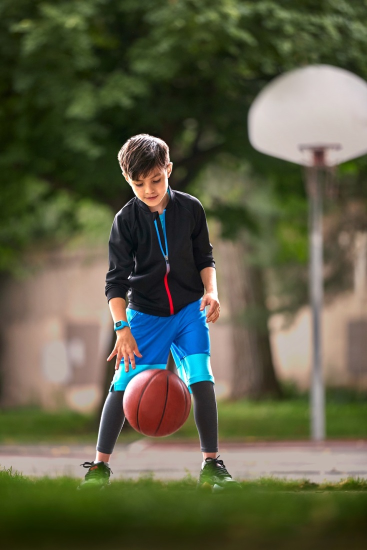 Αγοράκι παίζει με μπάλα μπάσκετ σε εξωτερικό χώρο