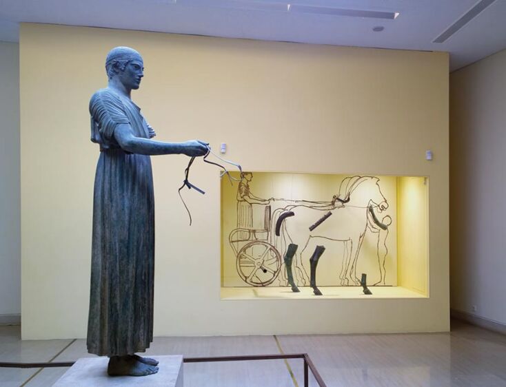 Ο Ηνίοχος των Δελφών.  Χάλκινο άγαλμα 480-460 π.Χ. (Αρχαιολογικό Μουσείο Δελφών). Αποτελούσε μέρος ενός μεγάλου αφιερώματος το οποίο περιλάμβανε και τέθριππο. 