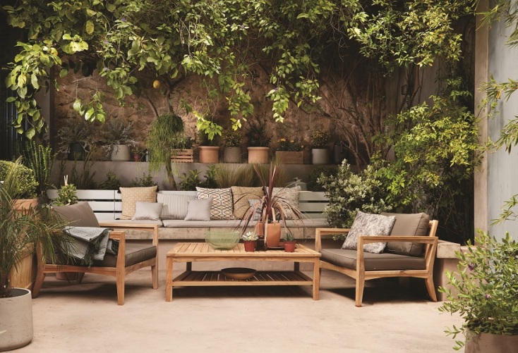 Καναπέδες και τραπέζι σε αυλή με πράσινα φυτά