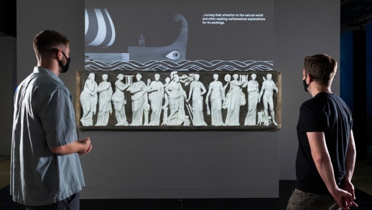 Παρακολουθώντας ένα ανιμέισιον που προβάλλεται πάνω σε σαρκοφάγο στην έκθεση "Αρχαίοι Έλληνες: επιστήμη και σοφία". Οι 9 μούσες, που συνοδεύονται από τον Απόλλωνα και την Αθηνά, συμβολίζουν την ευφυία και την κουλτούρα του νεκρού που τάφηκε στη σαρκοφάγο