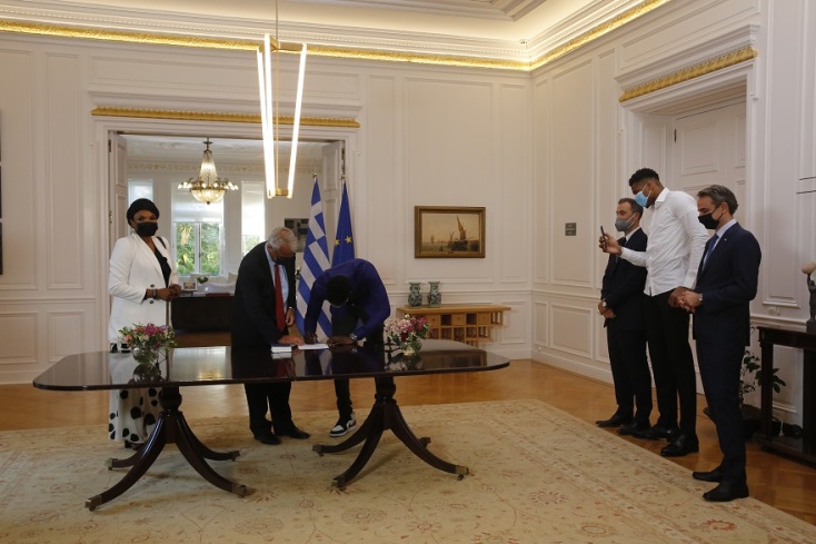 Η Βερόνικα και ο Άλεξ Αντετοκούνμπο υπογράφουν κατά τη διάρκεια της τελετής πολιτογράφησής τους, παρουσία του πρωθυπουργού Κυριάκου Μητσοτάκη και του Γιάννη Αντετοκούνμπο, στο Μέγαρο Μαξίμου