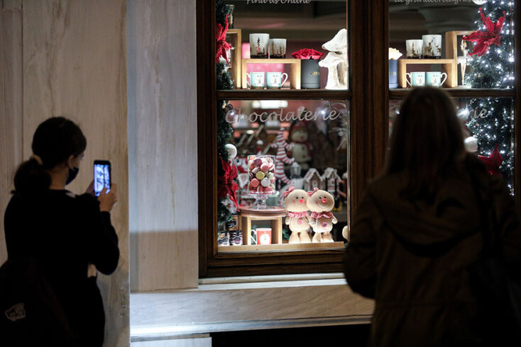 Πολίτες βγάζουν φωτογραφία βιτρίνα καταστήματος στην Αθήνα που έχει χριστουγεννιάτικο στολισμό