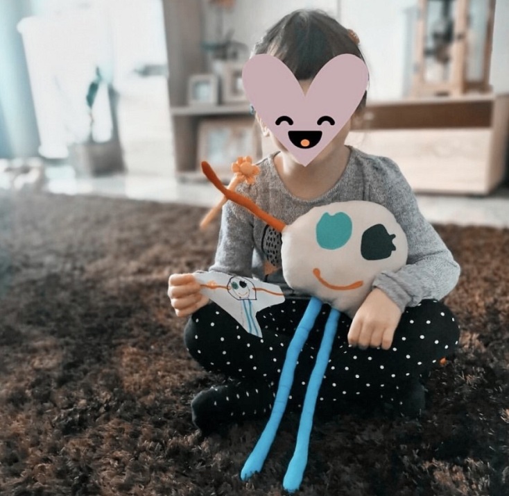 Παιδάκι κρατάει ζωγραφιά και κουκλάκι