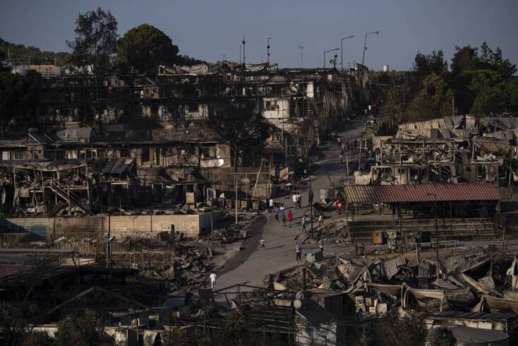 Πρόσφυγες και μετανάστες περπατούν στον κατεστραμμένο από τη φωτιά καταυλισμό της Μόριας, 9 Σεπτεμβρίου 2020