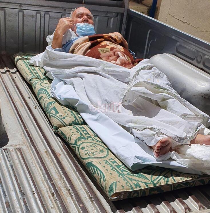 Ηλικιωμένος τυλιγμένος με σεντόνια επιβιβάζεται με τη βοήθεια ανδρών σε καρότσα αγροτικού στην Κρήτη