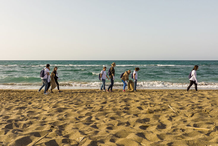 Άνθρωποι μαζεύουν σκουπίδια από παραλία