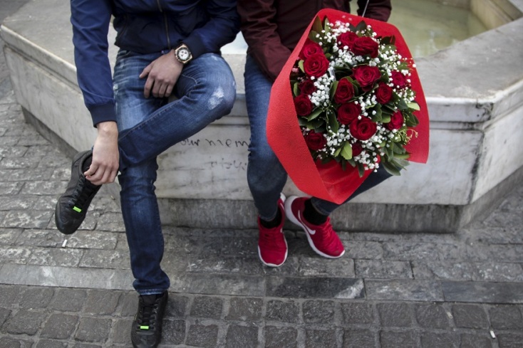 Ένας άνδρας κρατάει μια ανθοδέσμη με κόκκινα λουλούδια. 