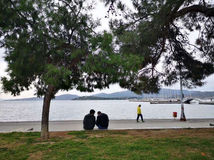 Δύο άνδρες κάθονται σε πεζούλι στην παραλία του Βόλου