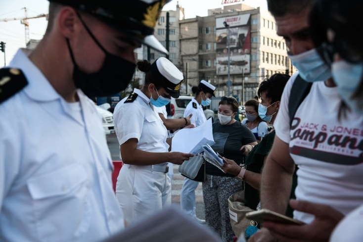 Ταξιδιώτες αναμένουν την επιβίβασή τους σε πλοίο κρατώντας στα χέρια κινητό ή έγγραφα που χρειάζονται 