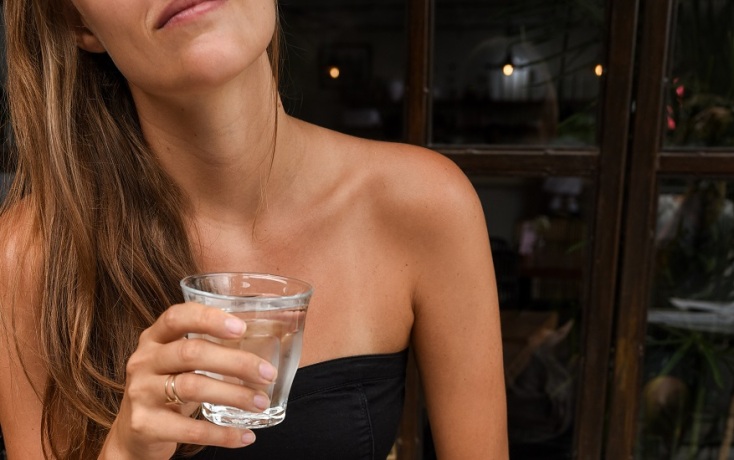 Γυναίκα κρατάει γυάλινο ποτήρι με νερό