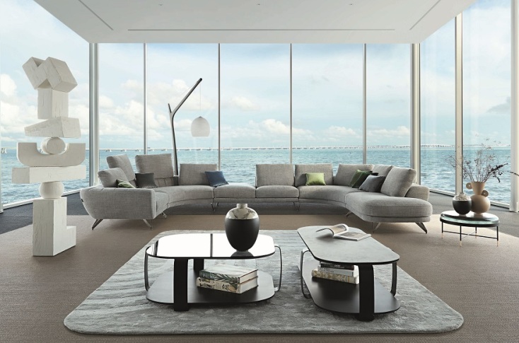 Σαλόνι με καναπέδες, τραπεζάκια, χαλί και τζαμαρία που φαίνεται θάλασσα