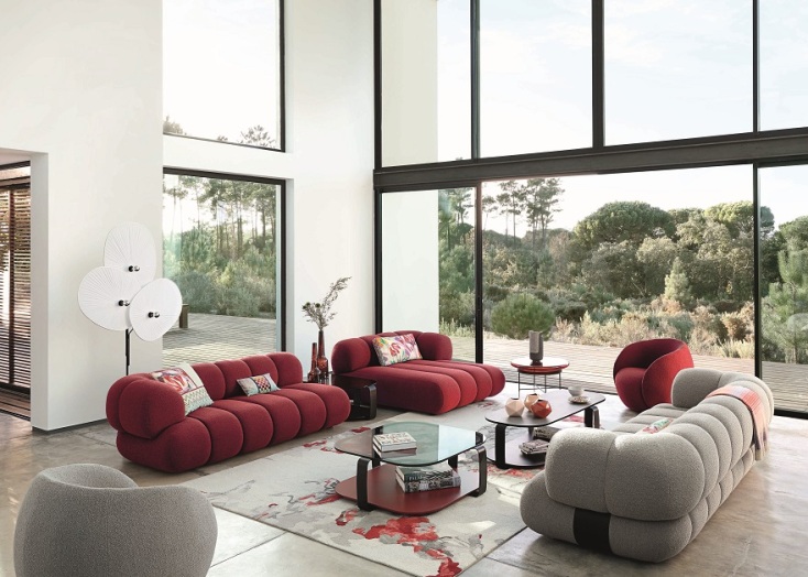 Σαλόνι με καναπέδες, τραπεζάκια, χαλί και τζαμαρία που φαίνονται δέντρα