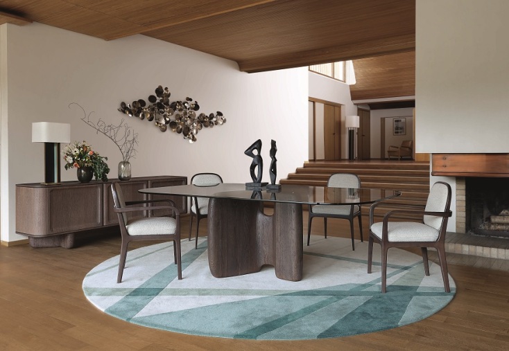 Τραπεζαρία με γυάλινη επιφάνεια, ξύλινες καρέκλες, χαλί, τζάκι στα δεξιά και σκάλες στο βάθος