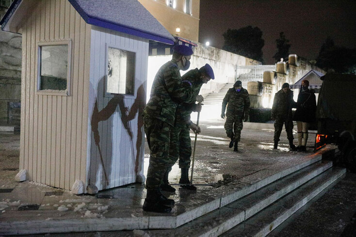 Μνημείο Αγνώστου Στρατιώτη - Σύνταγμα: Στρατιώτες με μάσκα για τον κορωνοϊό σπρώχνουν το χιόνι με σκούπες, καθώς η κακοκαιρία «Μήδεια» βρίσκεται σε εξέλιξη