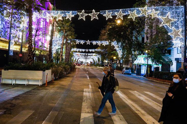 Πολίτες με μάσκα για τον κορωνοϊό διασχίζουν την Πανεπιστημίου, που έχει πλέον νέο χριστουγεννιάτικο στολισμό 
