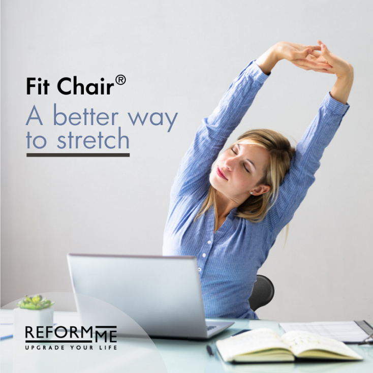 Γυναίκα καθισμένη σε καρέκλα-μπάλα Fit-Chair® μπροστά σε γραφείο τεντώνει τα χέρια της προς τα πάνω