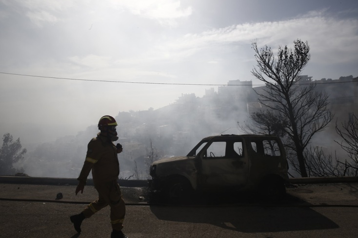 Φωτιά τώρα στη Βούλα: Πυροσβέστης περνά μπροστά από καμένο όχημα