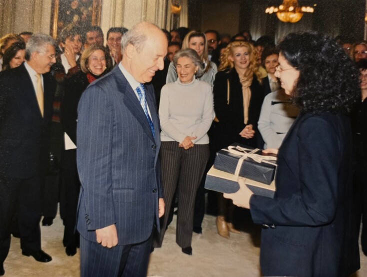 «Ιανουάριος 2004. Η τελευταία συνάντηση όλου του προσωπικού. Έχει ήδη ανακοινώσει ότι αποχωρεί. Είχα την ιδέα ότι ως δώρο του προσφέραμε την εικόνα μας. Ένα άλμπουμ φωτογραφιών από αυτά τα χρόνια. Με όλους τους συνεργάτες μέσα στην καθημερινότητα. Από τον άτυπο επικεφαλής Ν. Θέμελη έως τους μοτοσυκλετιστές, τις κυρίες της καθαριότητας. Είχε χαρεί και συγκινηθεί πολύ», λέει η Λίλιαν Μήτρου δίνοντας μάς προς δημοσίευση τη φωτογραφία 