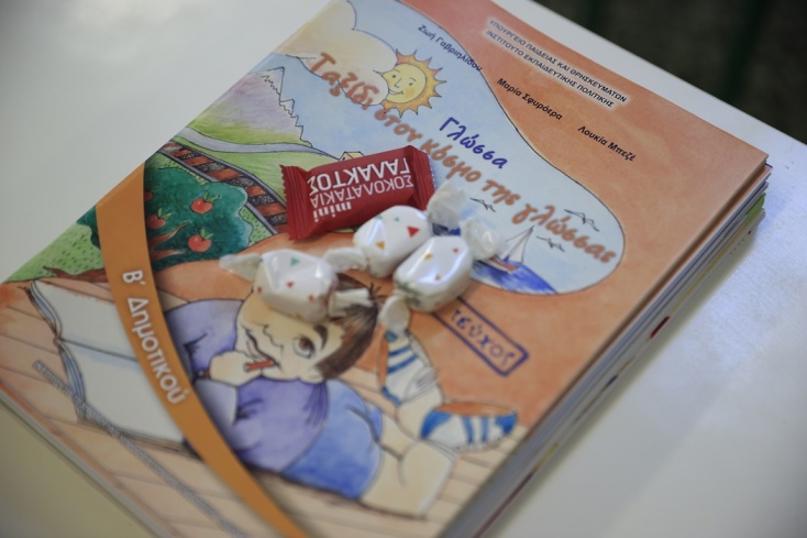 Σχολικό βιβλίο που έχει πάνω του σοκολατάκι και καραμέλες