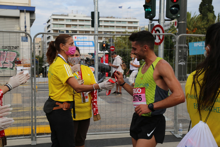 Εθελοντής παραδίδει το μετάλλιο σε δρομέα που έχει τερματίσει. 